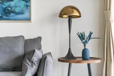 a lamp sitting on a table next to a couch at Lovely 1BR flat wBalcony Gym & Pool in JVC in Dubai
