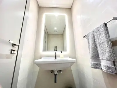 a white bathroom with a sink and a mirror at 50 Shades of Grey Luxury Apartment near Beach in Dubai