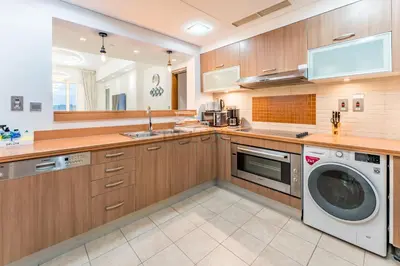 a kitchen with wooden cabinets and a washer and dryer at Glance at the Royal Atlantis Right by Dubai Top Spots 2BR, Marina Apartments 3, Palm Jumeirah by Deluxe Holiday Homes in Dubai