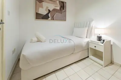 a white bedroom with a bed and a night stand at Glance at the Royal Atlantis Right by Dubai Top Spots 2BR, Marina Apartments 3, Palm Jumeirah by Deluxe Holiday Homes in Dubai