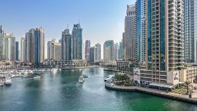 a river with boats in a city with tall buildings at Breathtaking Marina 2BR in Iconic Cayan Tower - 7AB08 in Dubai