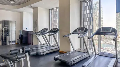 a row of treadmills in a gym with tall buildings at Breathtaking Marina 2BR in Iconic Cayan Tower - 7AB08 in Dubai