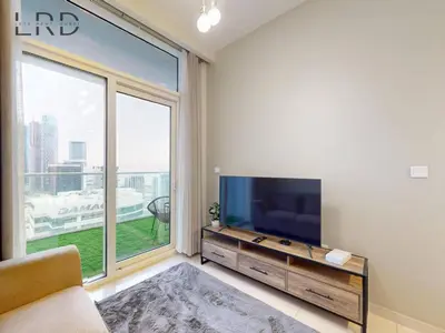 a living room with a tv and a large window at Elegant 1BR with Stunning Canal Views in Dubai