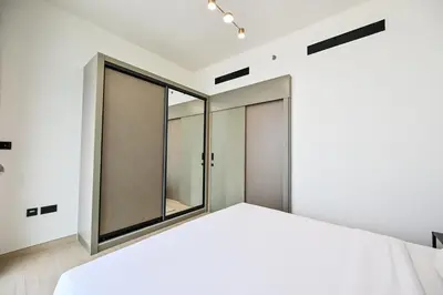 a bedroom with white walls and a large window at Stunning 1 Bdr luxury residence at JVC in Dubai