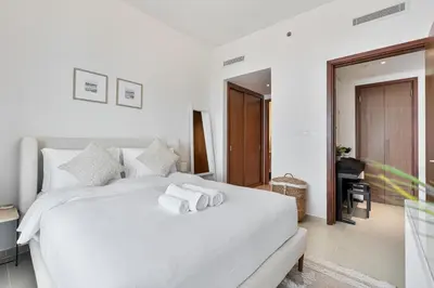 a bedroom with a white bed with towels on it at Stylish 1BR with Pool, Gym, BBQ Area & Playground in Dubai