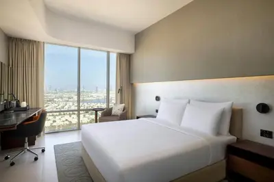 a hotel room with a large white bed and a desk at Hotel Local Dubai, Jumeirah Village Triangle, Autograph Collection in Dubai