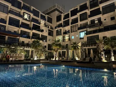a large apartment building with a swimming pool at night at Elite Business & Family Turnkey 433 Residence 2BR in OIA Motor City in Dubai