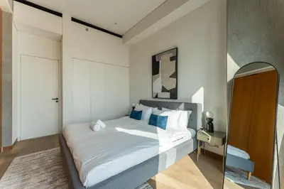 a bedroom with a large white bed with blue pillows at HAVN - 1 Bed at KOA Canvas, Access to Nasab Dubai in Dubai