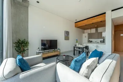 a living room with two white couches with blue pillows at HAVN - 1 Bed at KOA Canvas, Access to Nasab Dubai in Dubai