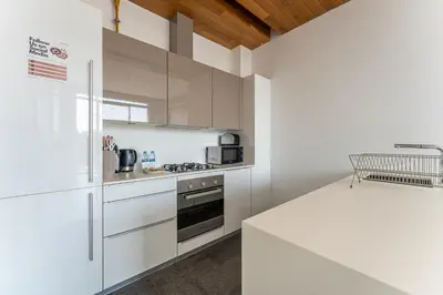 a white kitchen with a stove and a refrigerator at HAVN - 1 Bed at KOA Canvas, Access to Nasab Dubai in Dubai