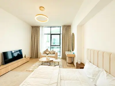 a bedroom with a bed and a tv and a table at Modern Studio Living in JVC's Regina Tower in Dubai