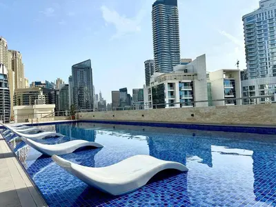 a large swimming pool with white chairs in a city at Cozy Studio at DEC Tower in Dubai