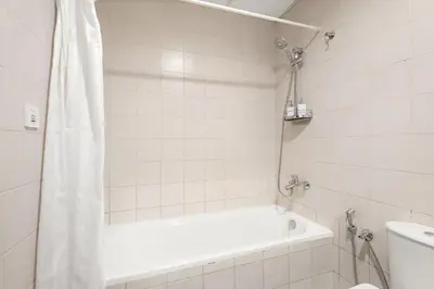 a white bathroom with a tub and a toilet at Cozy Studio at DEC Tower in Dubai
