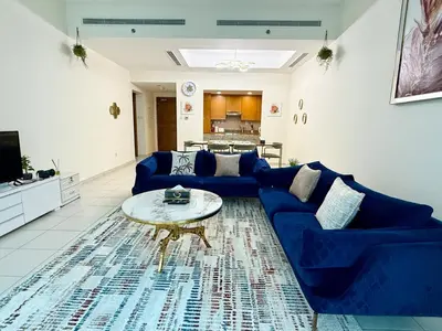 a living room with a blue couch and a table at Nivis find-Affordable & Spacious 1 BHK- 10 Mins to Dubai Mall in Dubai