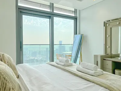 a white bed with towels on it in a room with a window at Exclusive 1BR with Iconic Views in Paramount Tower in Dubai