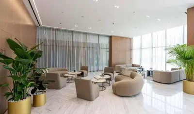 a lobby with couches and tables and plants at Modern Studio Apt Balcony & Free Parking Jvc in Dubai