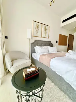 a bedroom with two beds and a table and a chair at Modern Studio Apt Balcony & Free Parking Jvc in Dubai