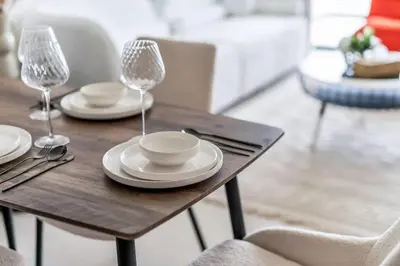 a wooden table with plates and wine glasses on it at Exceptional 1BR flat wBalcony Gym & Pool in JVC in Dubai
