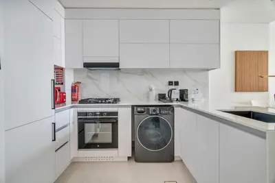a white kitchen with a washing machine in it at Exceptional 1BR flat wBalcony Gym & Pool in JVC in Dubai