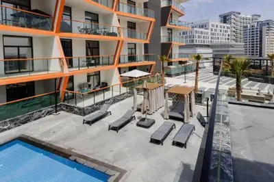 an apartment building with a swimming pool and lounge chairs at Contemporary 2 Bedroom Apartment in Dubai
