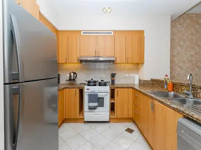 a kitchen with wooden cabinets and a white stove top oven at Exclusive 2BR in Al Yass Tower Dubai Marina - Private Terrace & Premium Community, Managed by Think Realty in Dubai