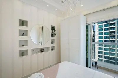 a white bedroom with a mirror and a window at High Floor Upgraded 2BR in JLT - Walk to Lake Park in Dubai