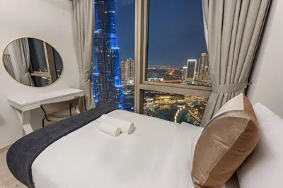 a bedroom with a bed and a large window at SML Vacation Homes - Sky High Apartments with Burj Khalifa and Dubai Fountain Views at Grande Signature, Downtown Dubai in Dubai