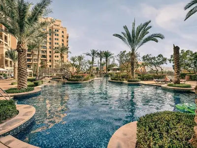 a pool at a resort with palm trees at New Fairmont Residence Private Beach club access Palm Jumeirah in Dubai