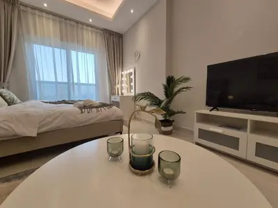 a living room with a table with two glasses on it at Studio in Hera towers, Dubai sports city in Dubai