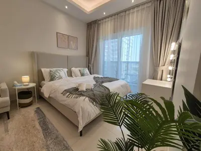 a bedroom with a bed and a large window at Studio in Hera towers, Dubai sports city in Dubai