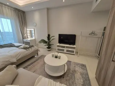 a bedroom with a bed and a tv and a table at Studio in Hera towers, Dubai sports city in Dubai