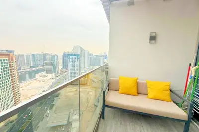 a couch on a balcony with a view of a city at Top Floor Studio with Sofa Bed Walk to Dubai Mall by Vibel in Dubai