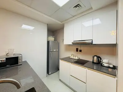 a kitchen with white cabinets and a stainless steel refrigerator at 1BHK LUXURY PRIVATE APARTMENT - Dubai Marina - 2 MIN WALK FROM TRAM in Dubai