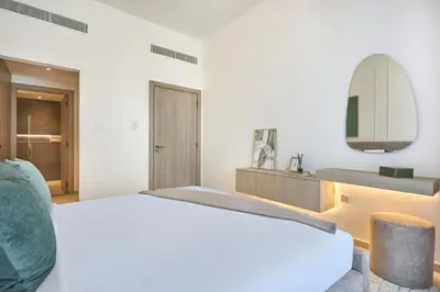 a white bedroom with a large bed and a mirror at Stylish 1BR Retreat in JVC Modern & Cozy Stay in Dubai