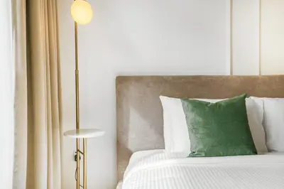 a bed with a green pillow and a floor lamp at Stylish 1BR Retreat in JVC Modern & Cozy Stay in Dubai