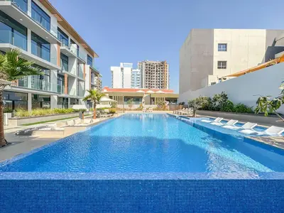 a large swimming pool with lounge chairs and a building at Stylish Studio Retreat Modern Stay in JVC in Dubai