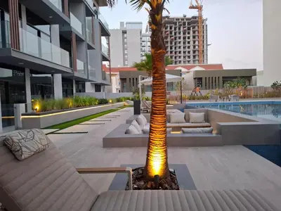 a palm tree with a light next to a pool at Stylish Studio Retreat Modern Stay in JVC in Dubai