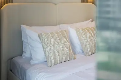 a white bed with four pillows on it at Luxury Meydan Studio Near Dubai Mall & Downtown in Dubai