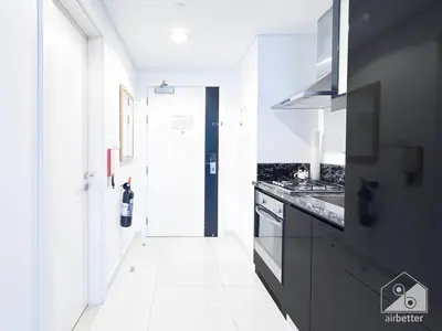 a kitchen with black cabinets and a white floor at Luxury Studio in Business Bay with Canal View in Dubai