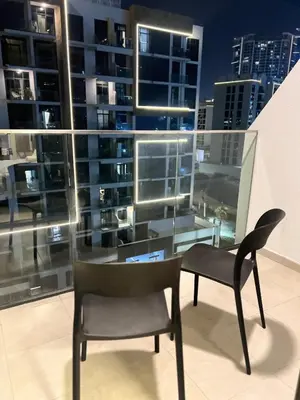 a chair and a table in front of a large window at Studios Apartment in Azizi Riviera in Dubai