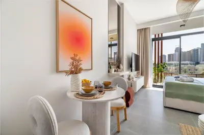 a living room with a table and chairs and a bedroom at Exquisitely designed studio in Oxford terraces JVC in Dubai