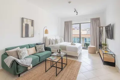 a living room with a green couch and a bed at Frank Porter - Lago Vista in Dubai