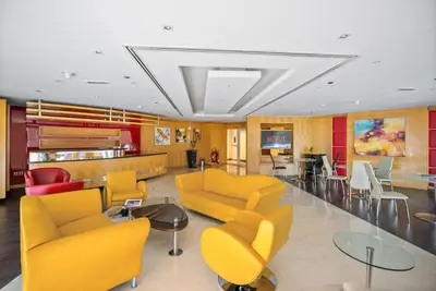 a waiting room with yellow chairs and a table at Stylish JLT Studio Lakeview Metro 5min & Marin in Dubai