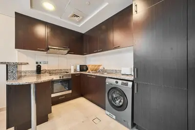 a kitchen with wooden cabinets and a washing machine at Chic Studio in Sky Gardens, DIFC Prime Location in Dubai