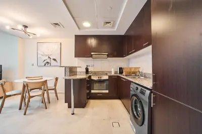 a kitchen with a washer and a table with chairs at Chic Studio in Sky Gardens, DIFC Prime Location in Dubai