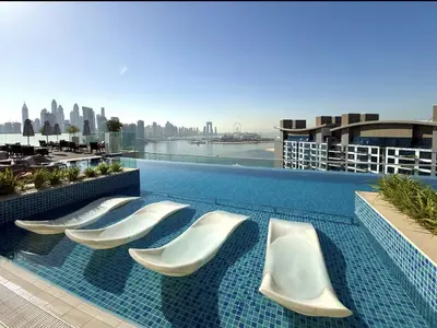 a swimming pool with white chairs on the roof of a building at Palm Jumeirah Beachfront apartment with Amazing Infinity Pool and private beach in Dubai