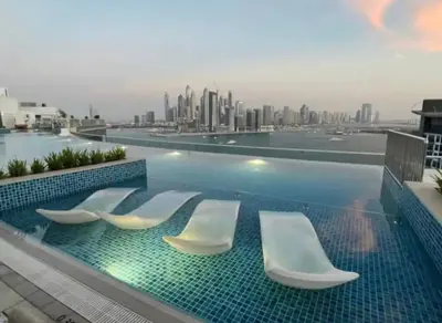 a swimming pool with four chairs and a city skyline at Palm Jumeirah Beachfront apartment with Amazing Infinity Pool and private beach in Dubai