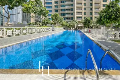 a blue swimming pool with a building in the background at LUX The Burj Khalifa Fountain View Suite 2 in Dubai