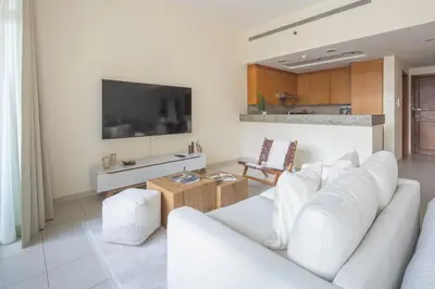 a living room with a white couch and a tv at Frank Porter - Bay Square in Dubai
