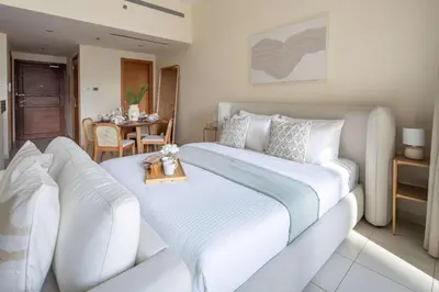 a bedroom with a large white bed and a table at Frank Porter - Bay Square in Dubai